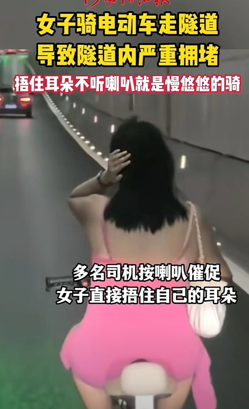 隧道里骑电动车，这个女子的胆量可见一斑，背对着一串长长的车龙，女子不堪忍受嘈杂的