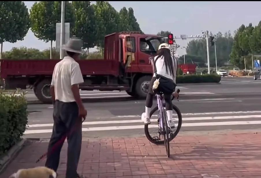 近日，一段骑车美女等红灯时不下车，看呆了一位遛狗大爷的视频在网上走红！
一开始，