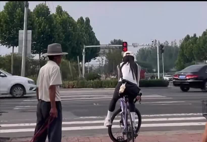 女子等红灯，这样骑自行车把后面的大爷看呆了