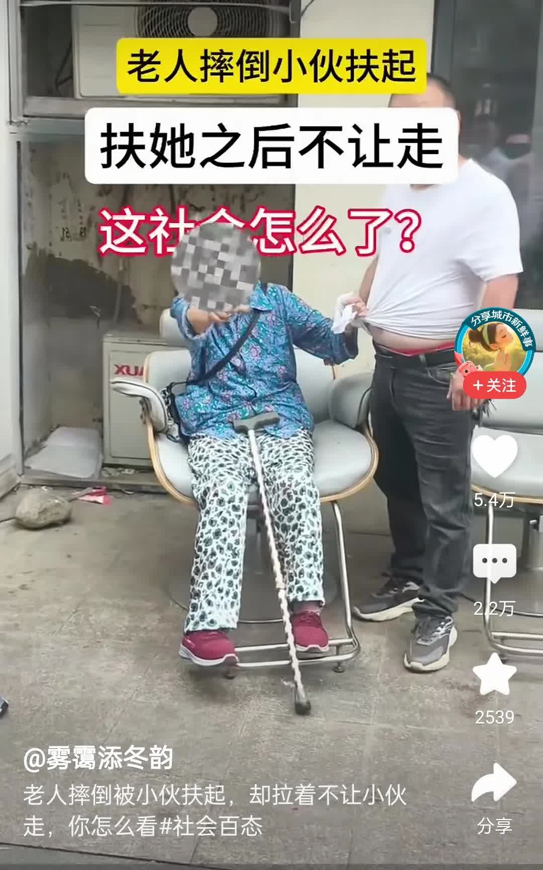 老人摔倒，男子扶起她后不让走。老人揪着男子的衣服不松手，男人站在那里无所适从。围