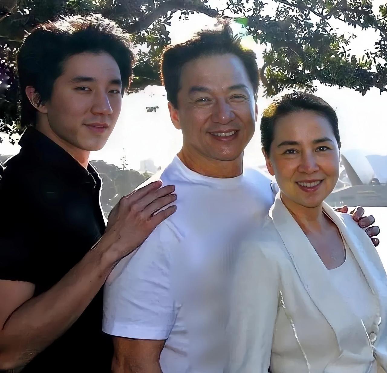 成龙一家三口侧身留影，照片中他们一家三口满脸笑容，侧身看着镜头，幸福甜蜜的一家人