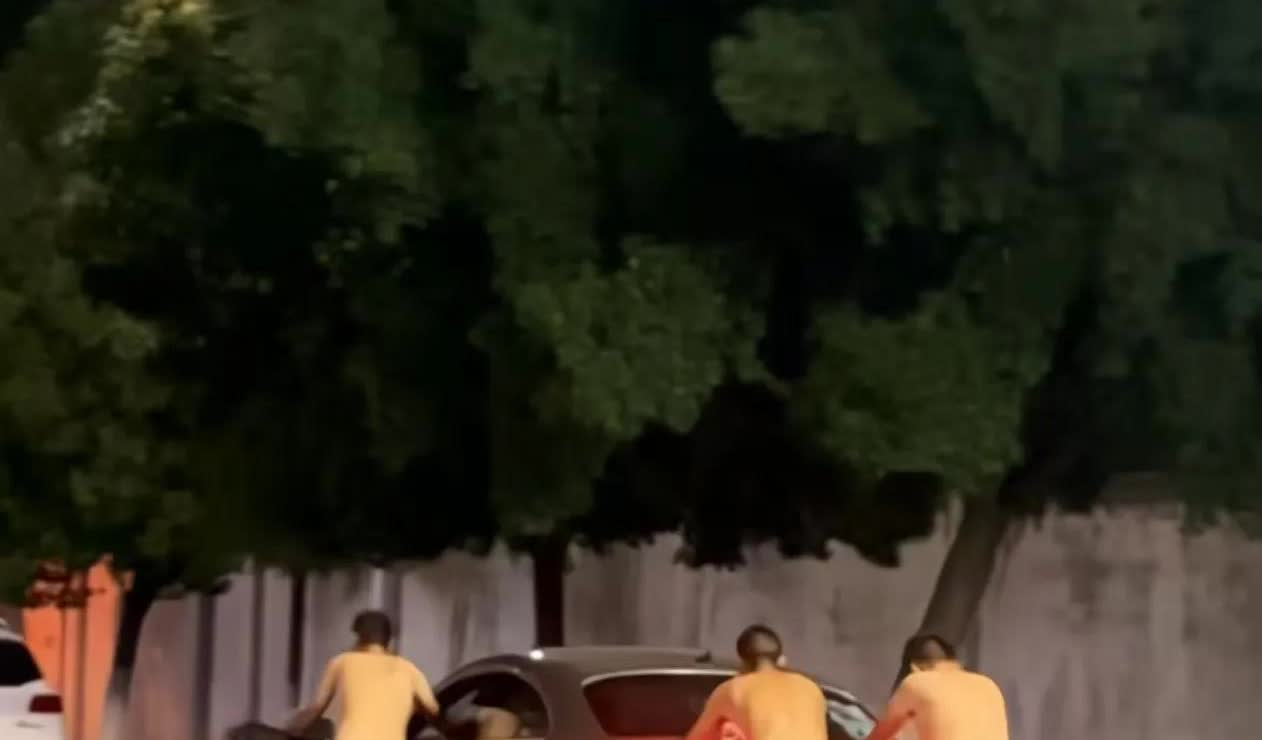 城郊公路的路灯下，三名男子推车门框走在机动车道。有一个主驾驶是没有喝酒的，他们自