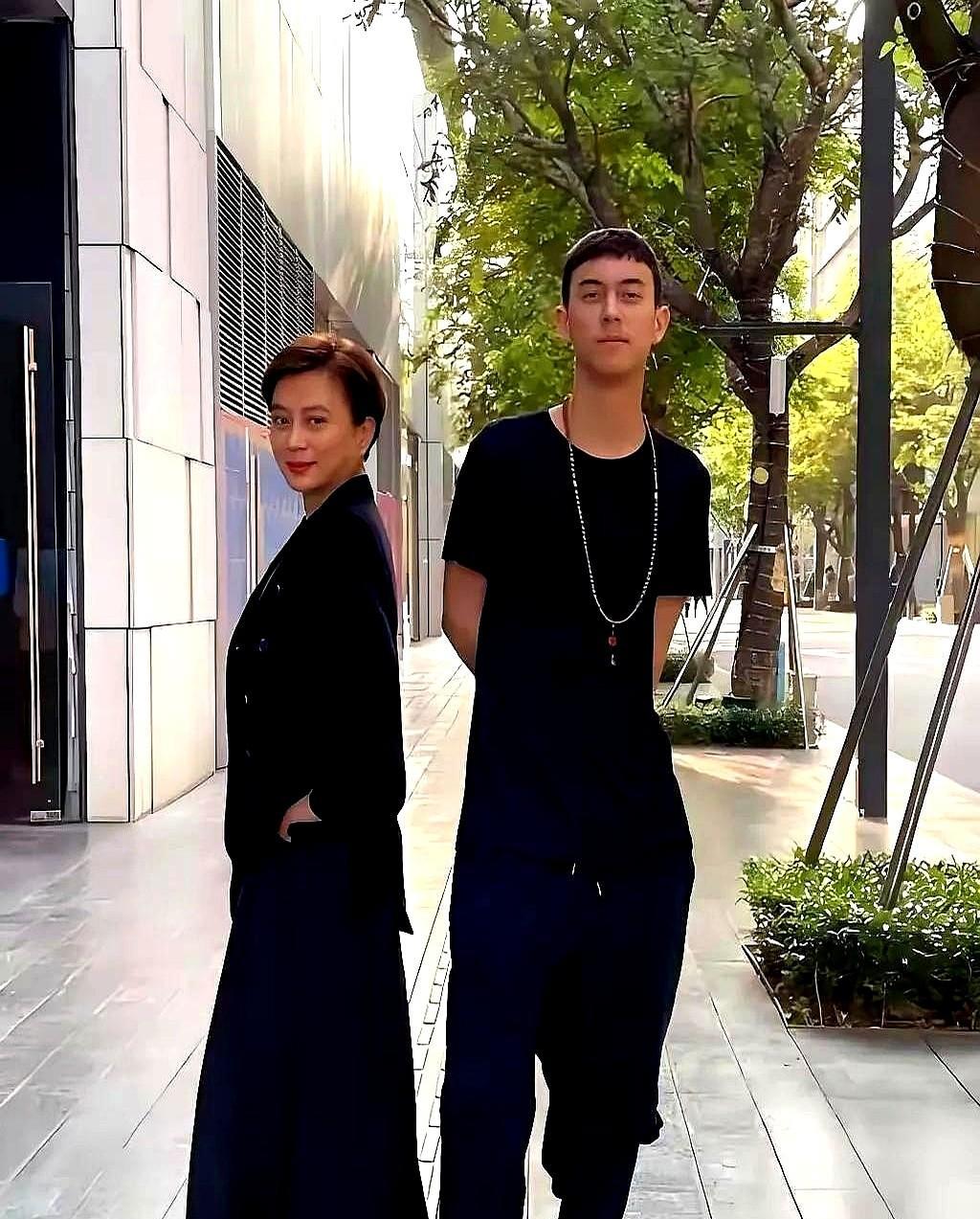 这是李玲玉与儿子在街头的合影照。
小伙子站在妈妈身边都快高出半个头了，肩膀宽得把
