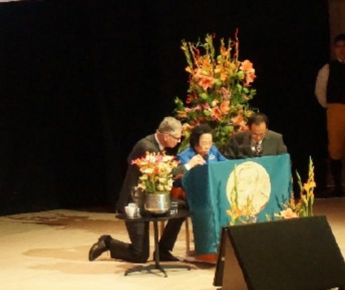 2015年，诺贝尔获奖者屠呦呦受邀发表演讲，然而，由于话筒线不够长，她只能弯着腰
