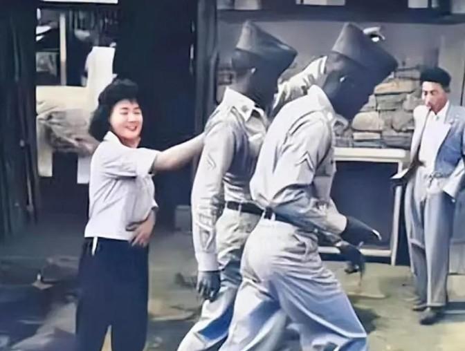1952年，一名南朝鲜女子给两名美军做完服务后，当着老公的面热情地送大兵们离开。