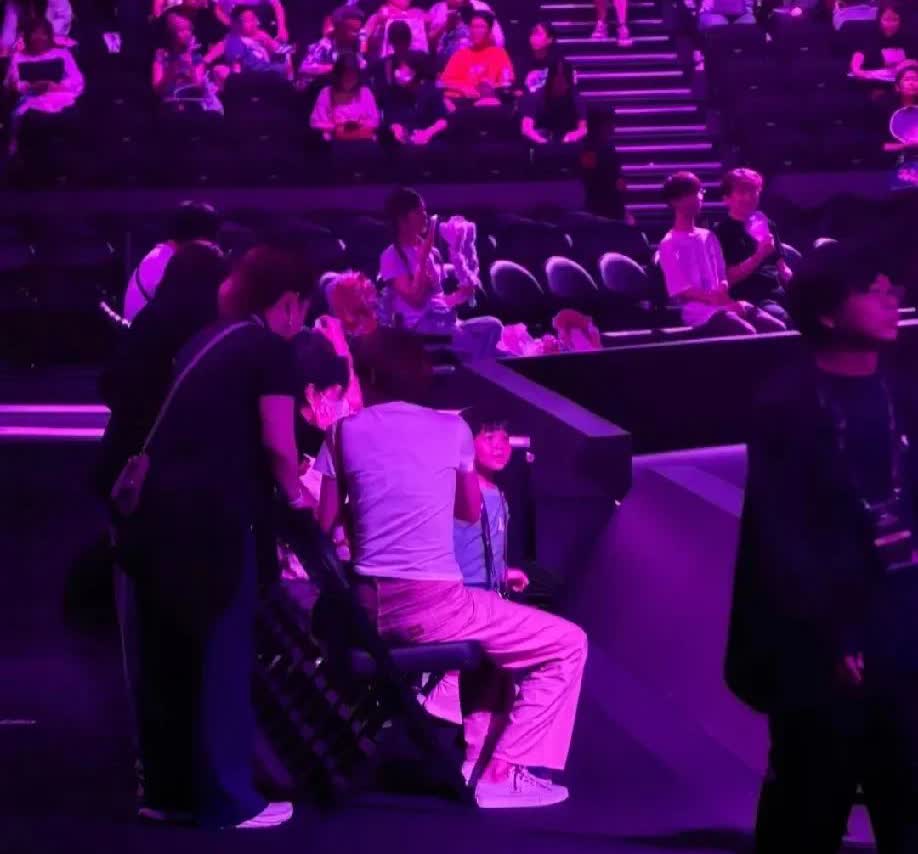 许昕的乒乓球俱乐部组织了一帮小朋友参加夏令营，姚彦带着小女儿坐前排看比赛。
马