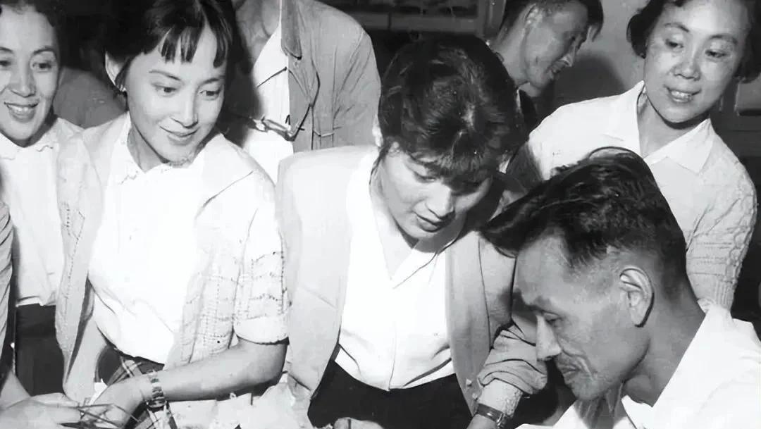 两位著名电影演员和两位著名越剧演员同框，她们正聚精会神看着工艺师傅雕刻木制品。有