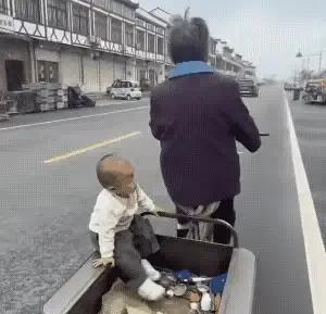 一大妈蹬着三轮车悠哉悠哉地晃在路上，让人不可思议的是三轮车厢里竟然坐了一个尿不湿
