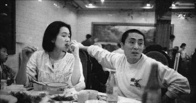 张艺谋和巩俐一起在餐厅就餐照，巩俐正用手拿着骨头啃，留着短发，面容清纯，只简单的