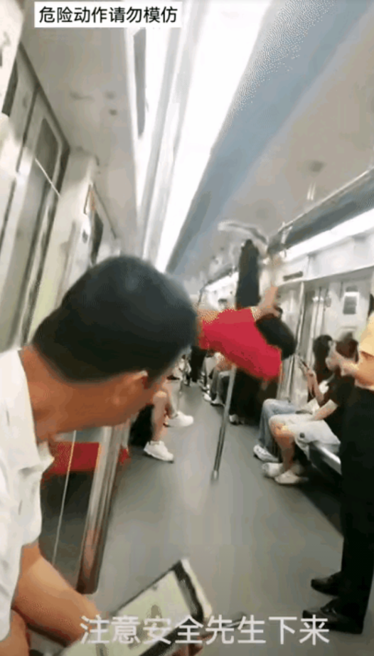 在地铁车厢里，一位穿红色T恤衫的老年人，把车厢内的乘客扶杆，当成了小区里的单杠在