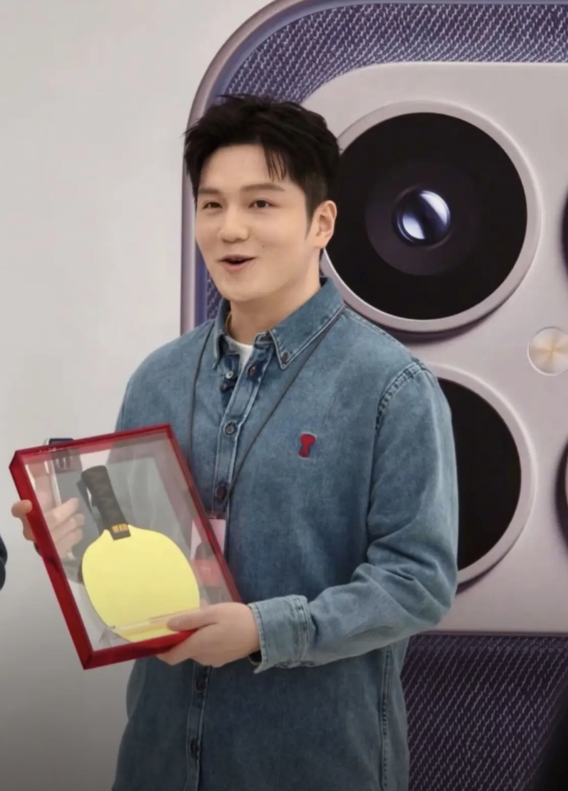 今天的樊振东一身的牛仔衣，深圳小米手机店，小米副总裁送给了东哥一个特殊的礼物—-