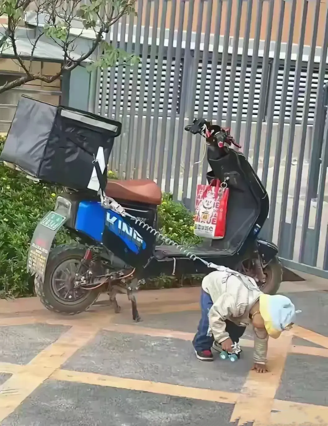这张照片让人看着有些心酸：外卖员爸爸进小区送外卖了，怕电动车上自己的孩子走丢了，