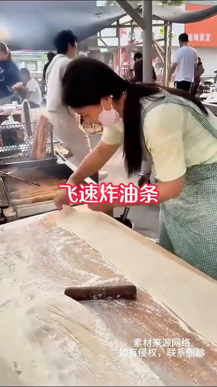 飞速炸油条。
在路边看到这一幕，眼前这位油条摊老板娘只见她抖面就像是抖被子一样顺