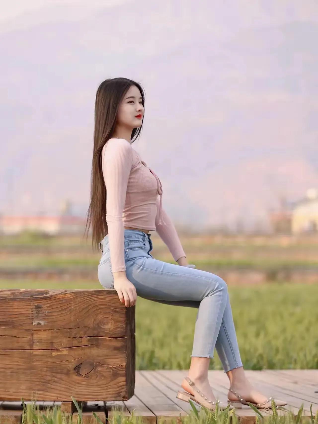 少女在田野间，静坐木箱旁，悠然自得。