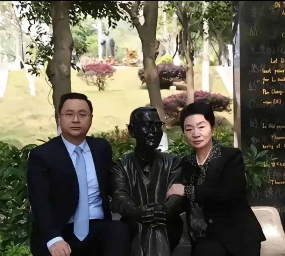 这是数学家陈景润的妻子由昆、儿子陈由伟扫墓时，和他的铜像合影的照片，两母子分坐在
