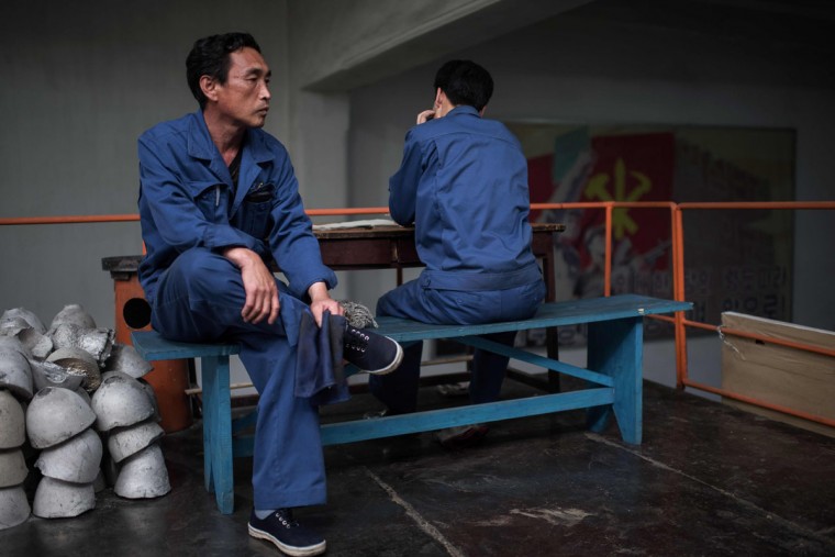 朝鲜工厂的工人，正在休息，穿着蓝色的工作服 。