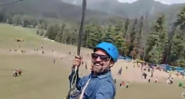 这是一个令人印象深刻的时刻——一位面带微笑的游客，戴着安全帽和太阳镜，在教练给他