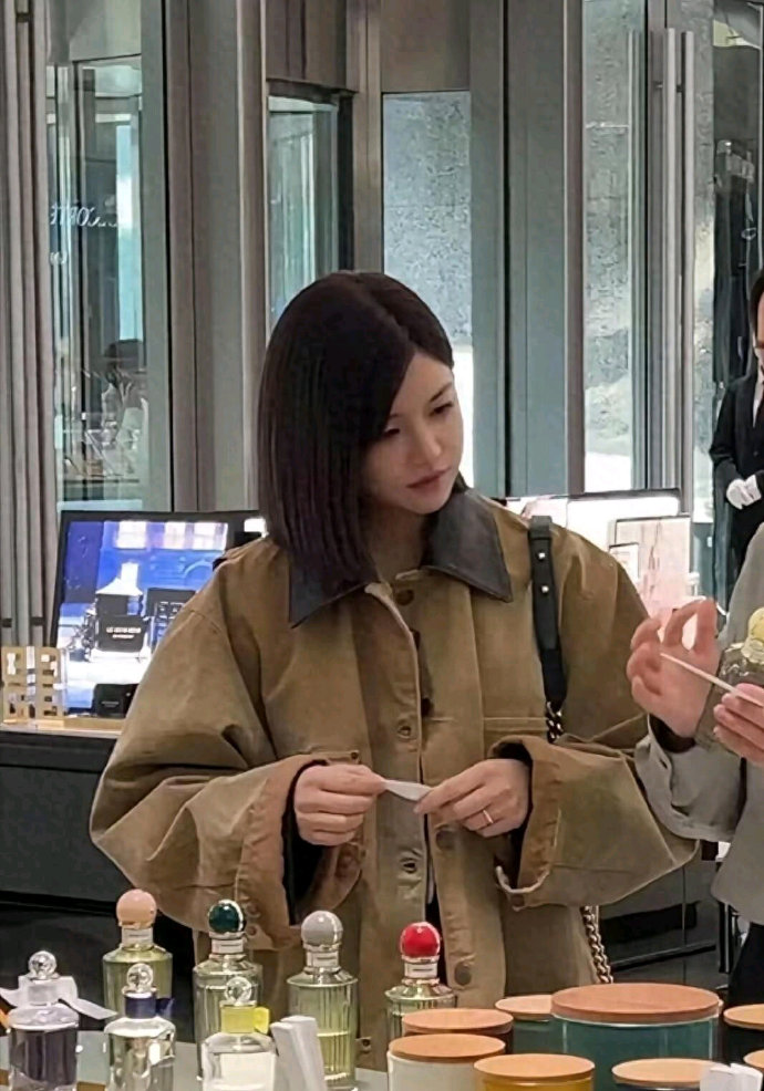 陈妍希身穿卡其色外套，背小香风链条包在商场挑选化妆品，漂亮甜美！