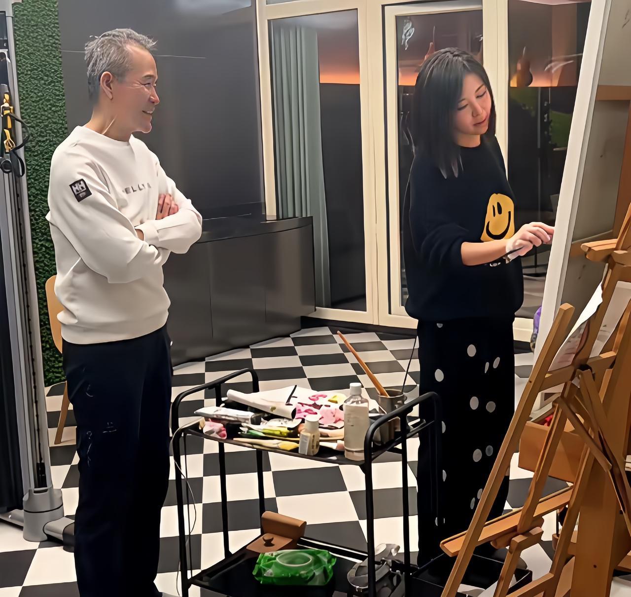 王石与田朴珺的旧照，田朴珺在家里画画，王石站在一旁观看，满脸的笑容，美滋滋的。