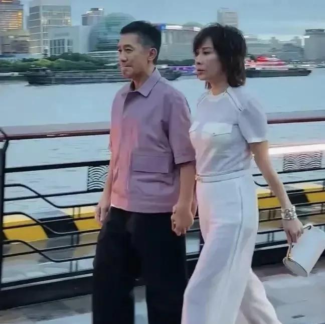 近日，梁朝伟与刘嘉玲现身上海，引发众人关注。活动现场，刘嘉玲一袭米白色立体剪裁套