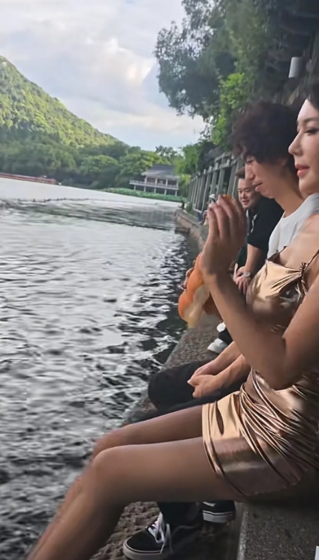龚玥菲庞麦郎后续，俩人坐在西湖边喂鱼。主要是龚玥菲拿着面包在喂，庞麦郎则坐在旁边