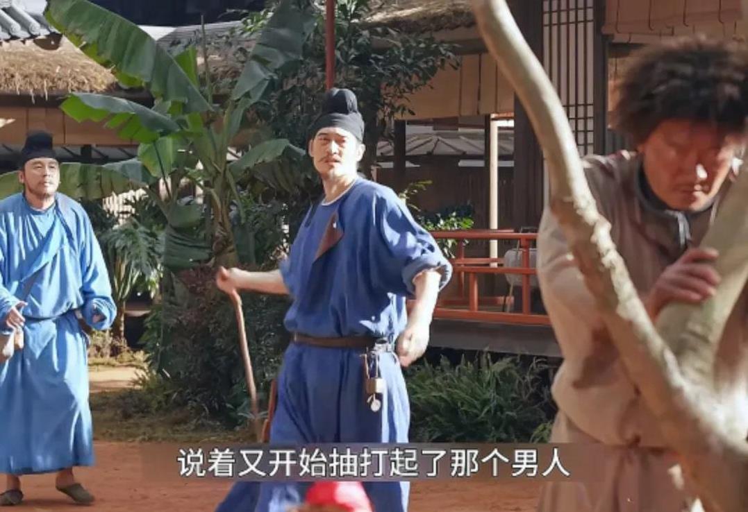 一名下人扶着树，管事的在用皮鞭抽他，只因他在米里拌了老鼠药，刺史喂鸡，把心爱的鸡