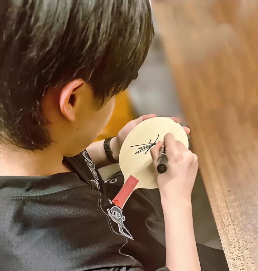 王楚钦在厦门备战乒超，一张签名路透照直接让粉丝吵翻了。
黑色新训练服裹着挺拔身板