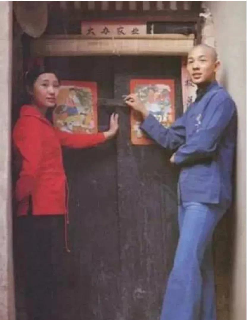 早期的李连杰还没成名前和一红衣女子合影，李连杰光头。蓝色开襟衬衫牛仔喇叭裤，时尚