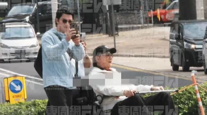 5月27日，89岁的谢贤外出晒太阳，坐轮椅拄拐杖，身体欠佳。他怕丑态被拍，常戴口