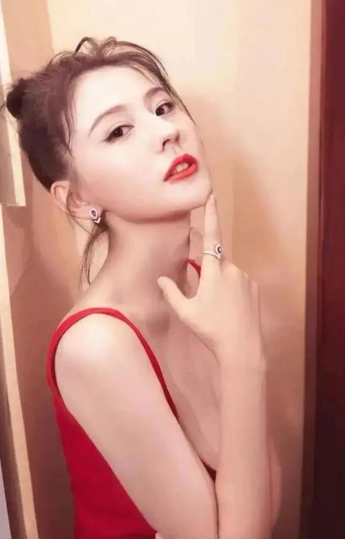 在光影交织间，热依扎似一团炽热燃烧的火焰，释放着令人难以抗拒的魅力。她身着红裙，