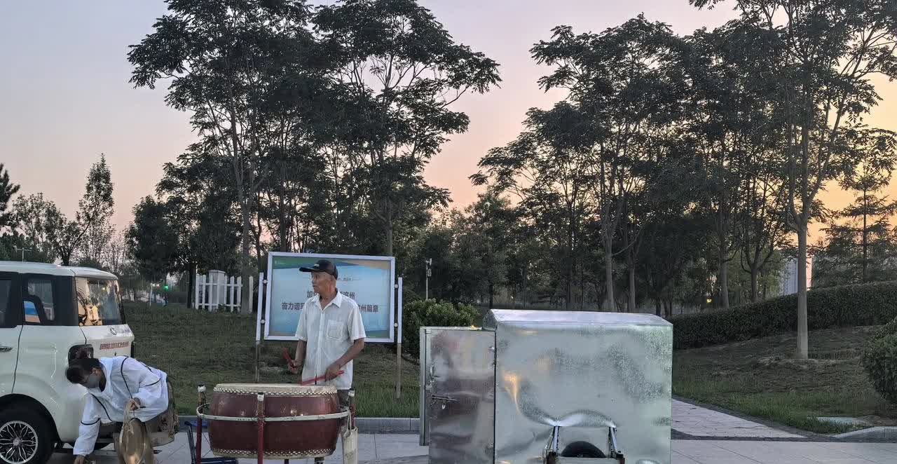 老人用自制拖车（身旁白铁盒子）把一个巨鼓拉到北海南门广场，起劲地敲打，一边还有一