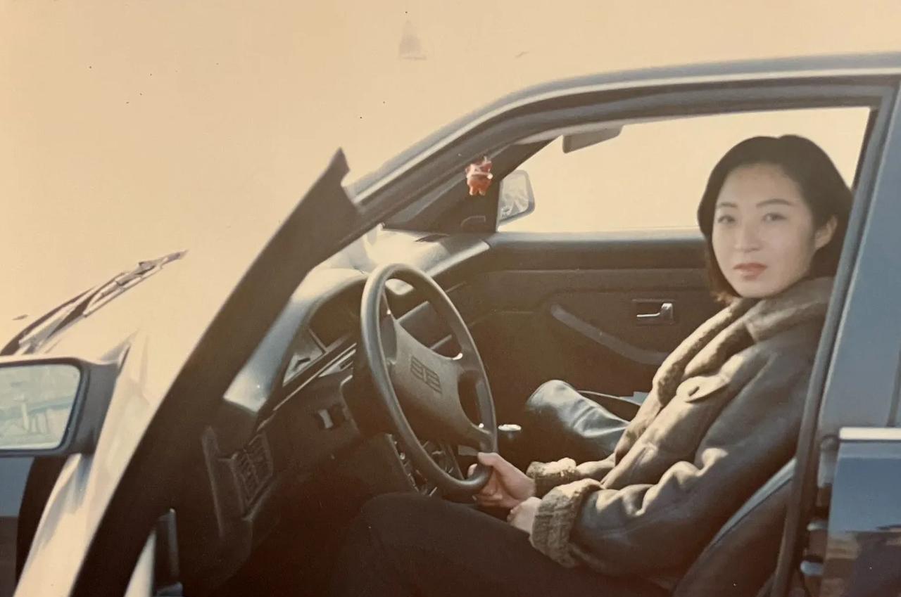 这个面容秀丽、身材婀娜且穿着时髦的女子坐在自家的私家车里，自信地看向车外，于是就