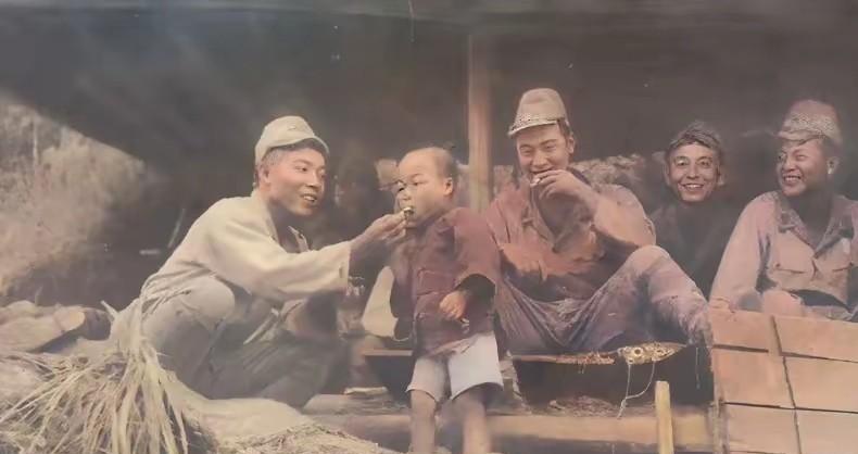 这是日寇当年拍摄的照片（后期上色），一个小鬼子正在给我们的一个小孩吃东西，其他鬼