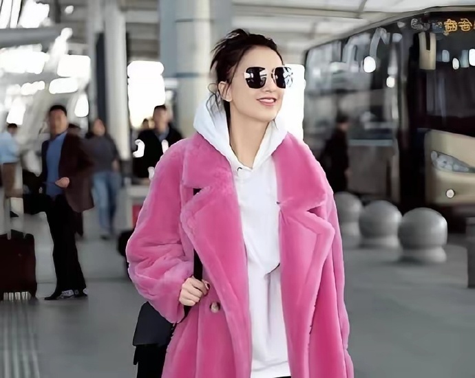 42岁黄圣依现身机场，她身穿粉色毛绒大衣搭配高马尾，皮肤白到发光，少女感十足，感