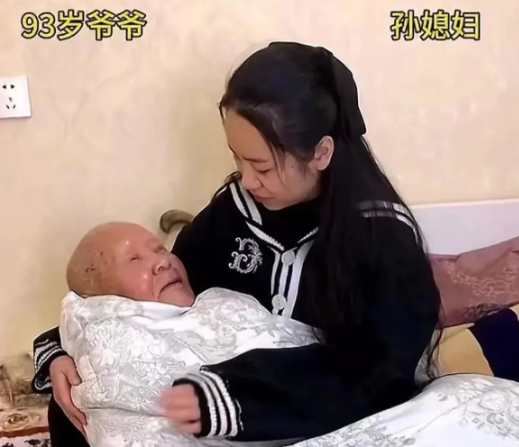 镜头记录下温馨一幕：年轻女子像哄孩子般，将白发苍苍的老人搂在怀中轻拍