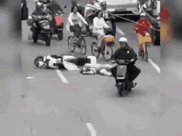骑电动车的女士不知道什么原因摔倒在地，已经爬不起来了，马路上车水马龙、人来人往，