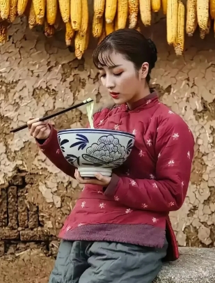  这是谁家的媳妇儿啊，端这么大个碗，坐在石头上吃饭，后面还有一排排的玉米，真是有