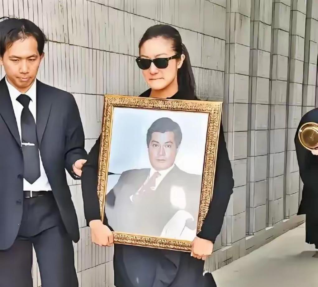 2011年，香港影视圈大佬邓光荣病逝，长女邓业炘捧着父亲的遗照的照片，尽管戴着墨