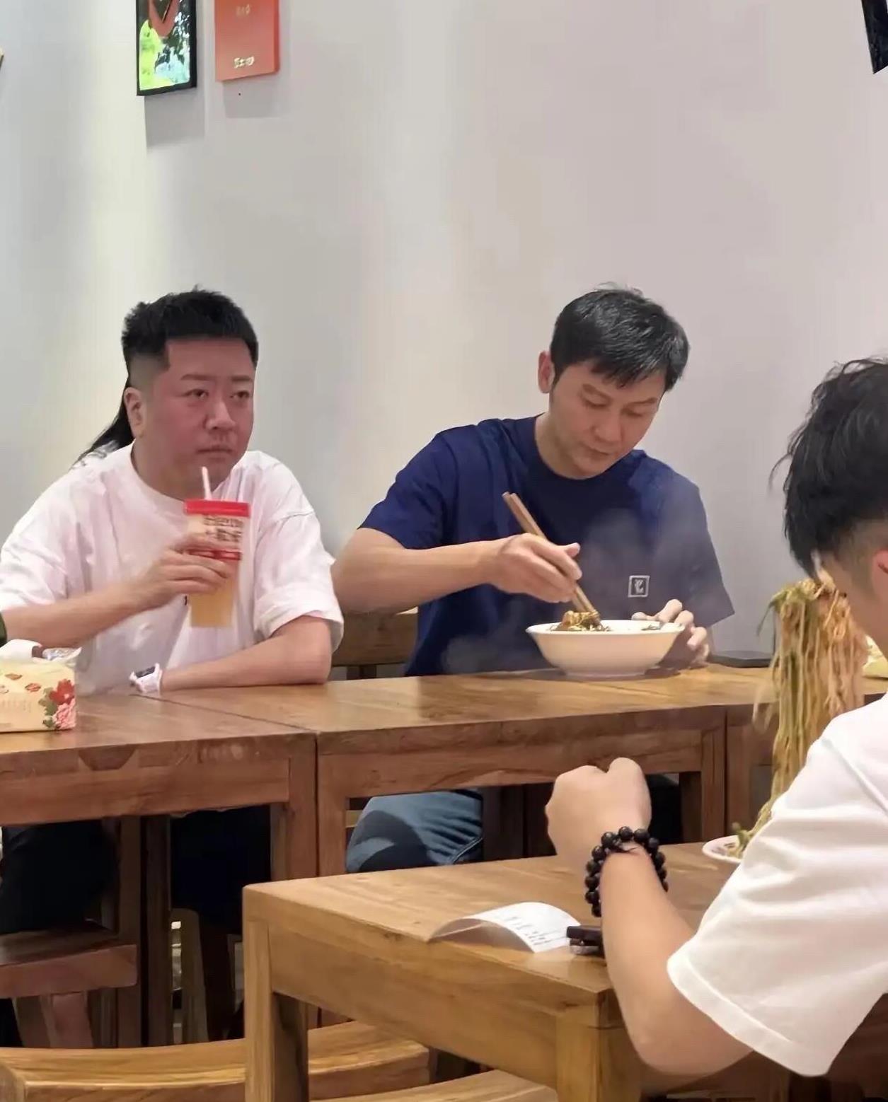 看一看这一位在喝饮料的男人，好淡定呀，估计他自己都不知道旁边坐着一位大明星在吃面
