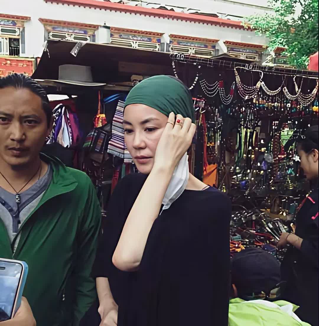 王菲在西藏祈福的样子，裹着绿色头巾，罩着黑色长袍，眉眼间透着难得的温和，像浸在酥