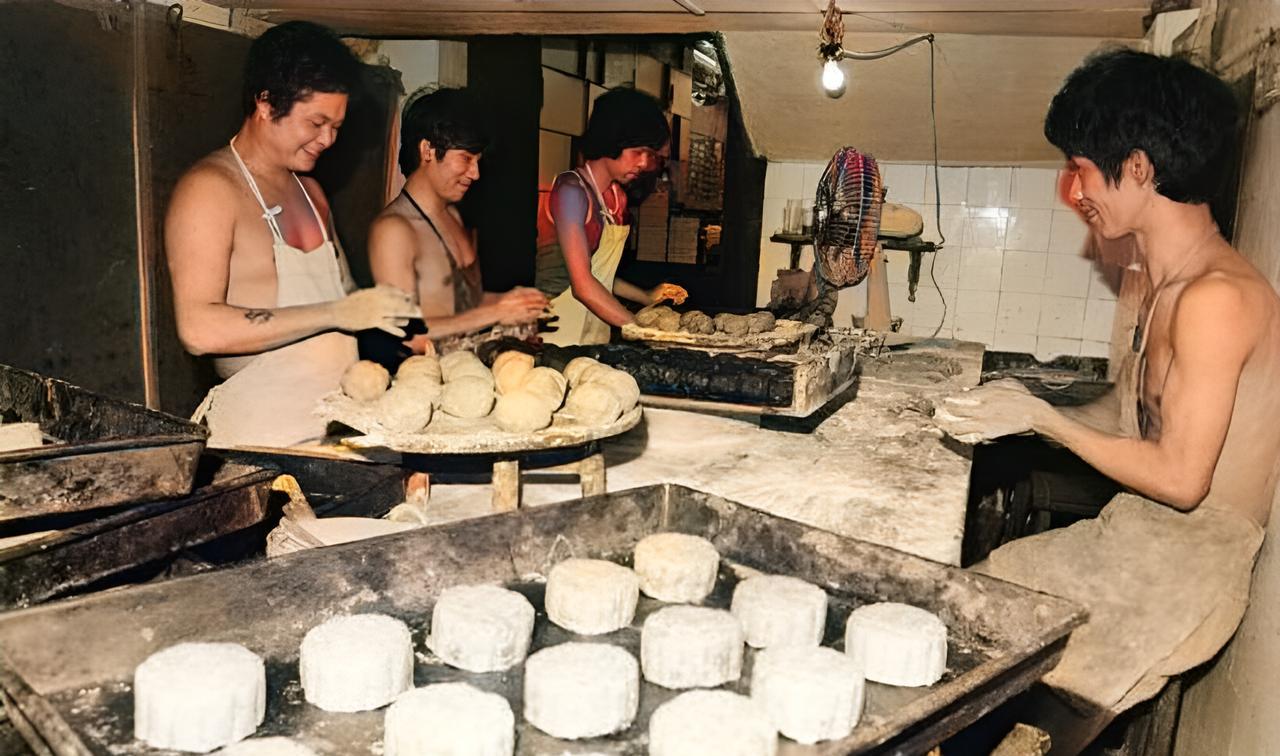 这是八十年代月饼小作坊里五名大汉赤着上身戴着围裙忙碌着制作月饼。许多人认为他们在