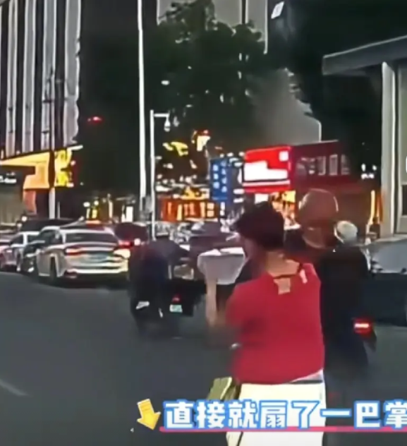 大爷拎着东西横穿马路，女子见其走路不利索，好心过去扶大爷，结果被反打一巴掌，眼镜