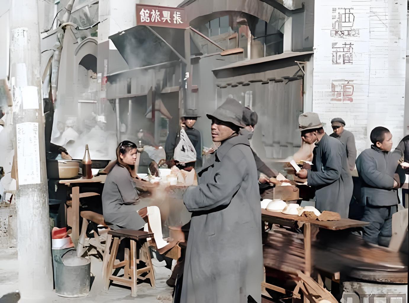 这是民国时期街头早点摊的场景。画面里，有人坐着用餐，有人站着交易，蒸腾的热气、简