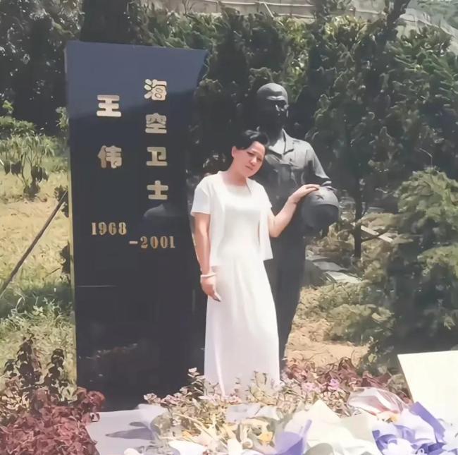 这是王伟烈士遗孀阮国琴，为丈夫扫墓时的照片，照片中，阮国琴站在王伟雕塑身旁，她的