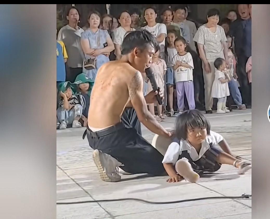 三岁女童街头卖艺，看哭读者和现场围观者。
只见一个30多岁的男人，拿了一个直径几