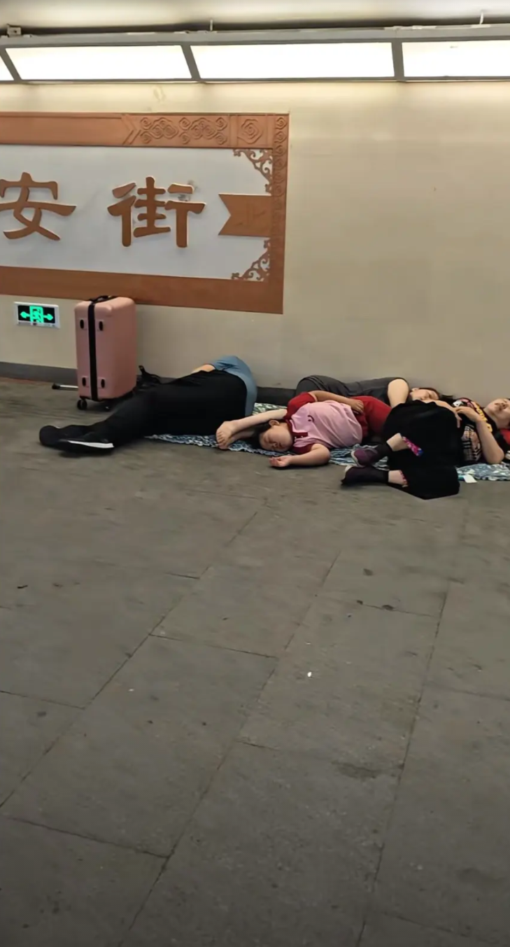 2025年7月11日晚上，北京长安街。
地下通道里，一家人正在休息。他们这是为了