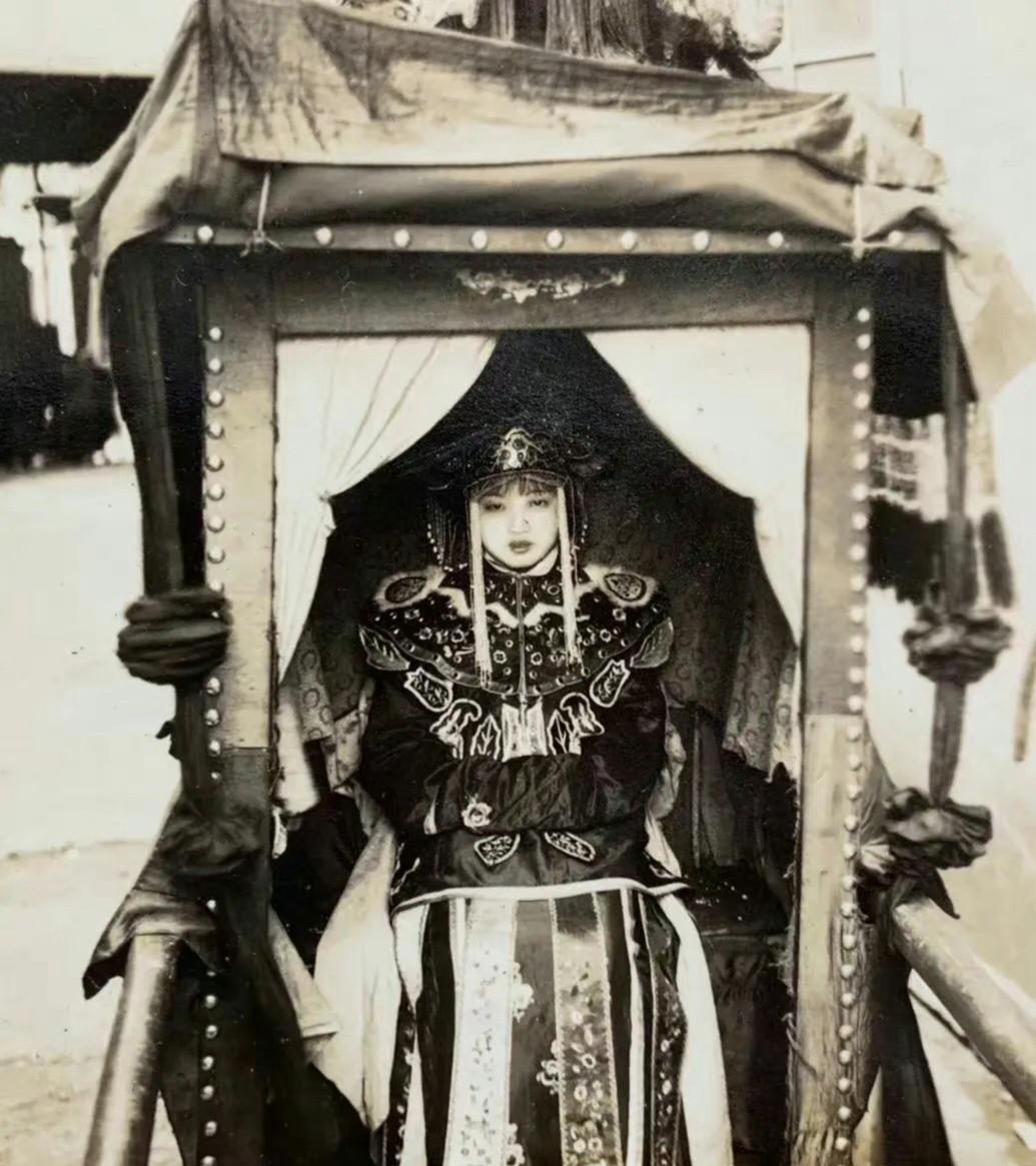 1942年民国时期，广州一位出嫁的美丽新娘子的照片，镜头中她坐在挂着红色彩绸的花