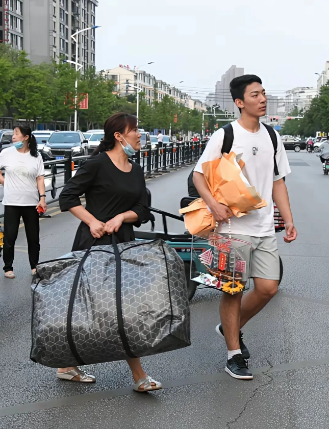 高考后，儿子手捧鲜花潇洒的走出了六亲不认的步伐，身边妈妈拿着大行李包的画面挺扎心