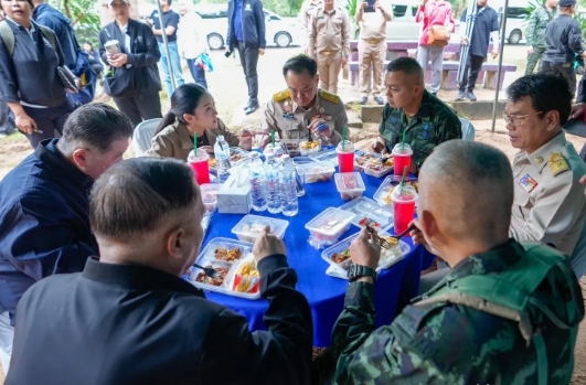 泰国总理同当地官员交谈，一起吃盒饭