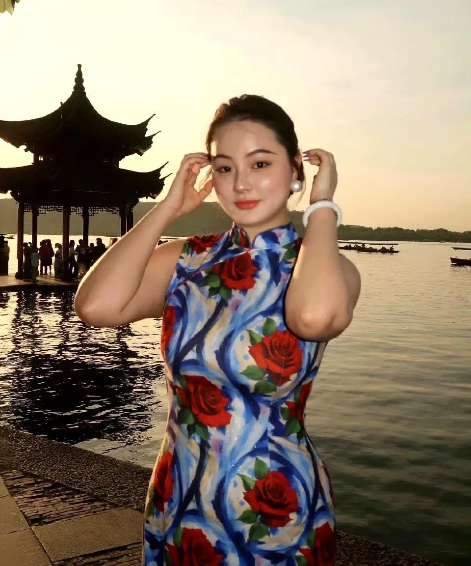 在西湖之畔，一位身着印花旗袍的女子，宛如从旧时光中缓缓走来的佳人。旗袍在她完美身